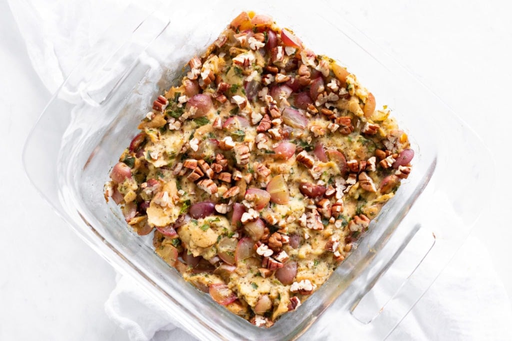 A pan of stuffing made with pecans and red grapes.
