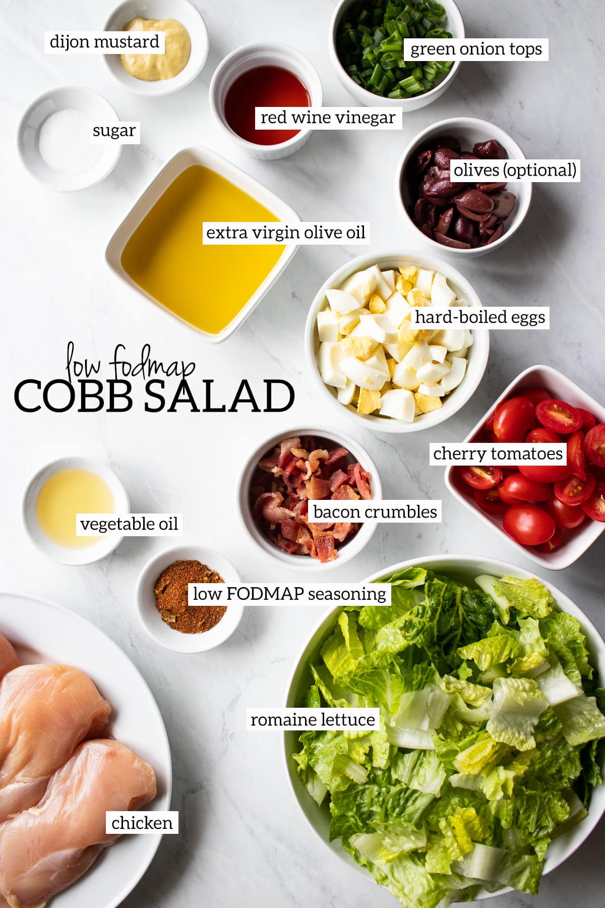 Ingredients needed for Low FODMAP Cobb Salad are measured out into individual white dishes.