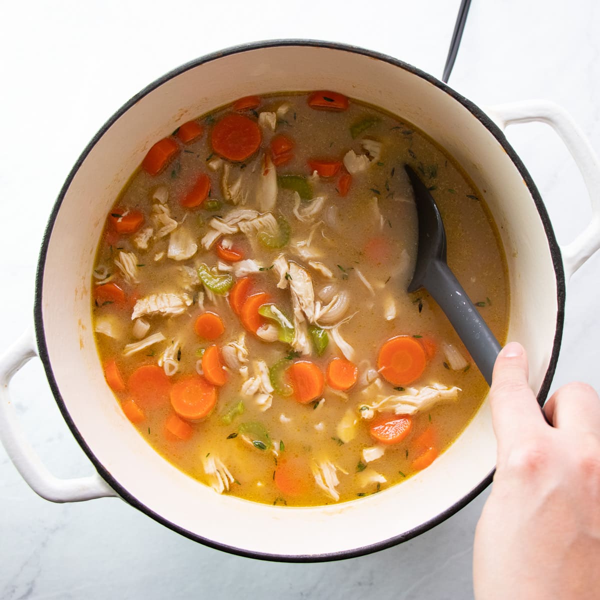 Stirring lemon juice and cubed cooked chicken into the white soup containing low FODMAP chicken noodle soup.