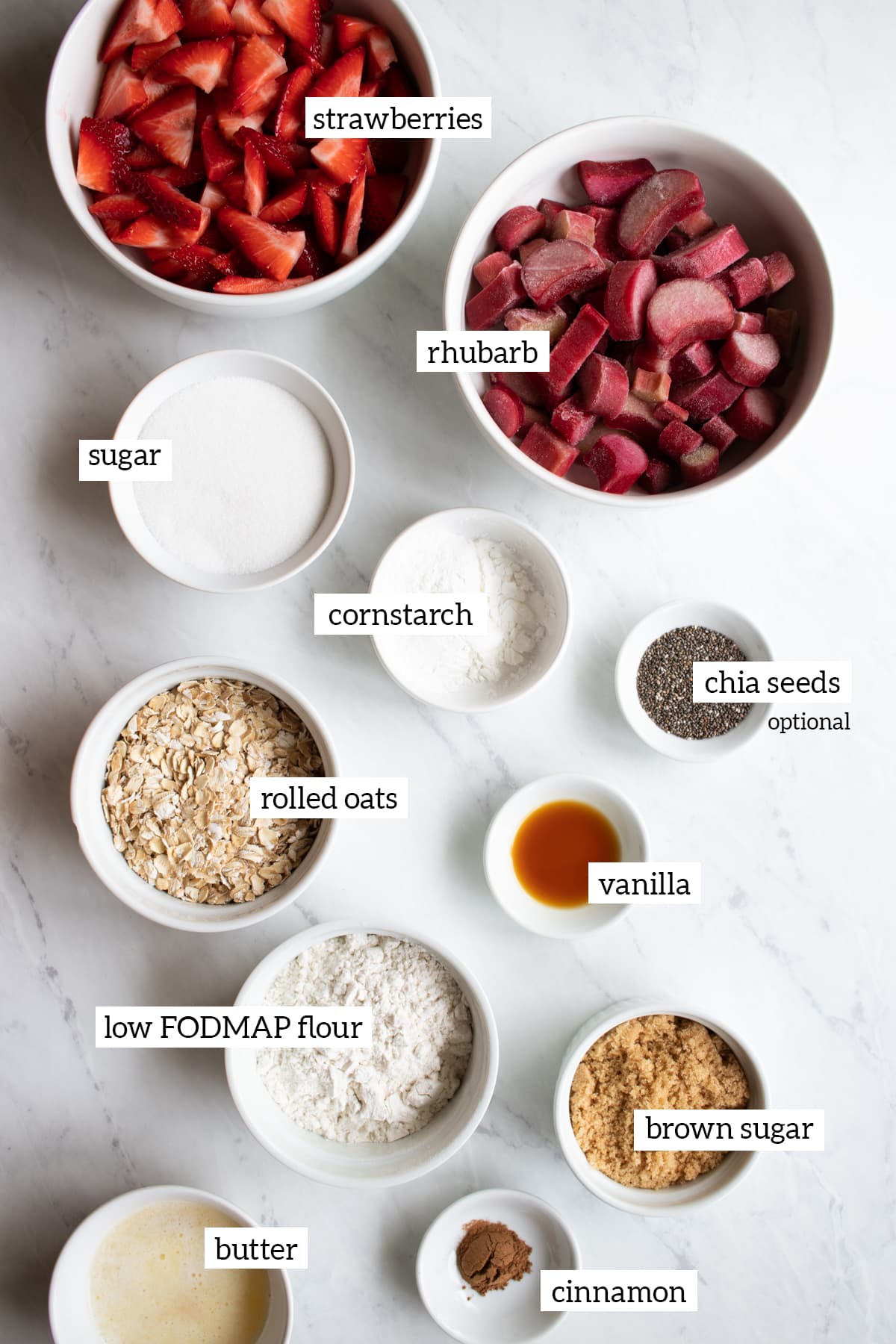 Ingredients needed to make this strawberry-rhubarb crisp are measured into small white bowls. 