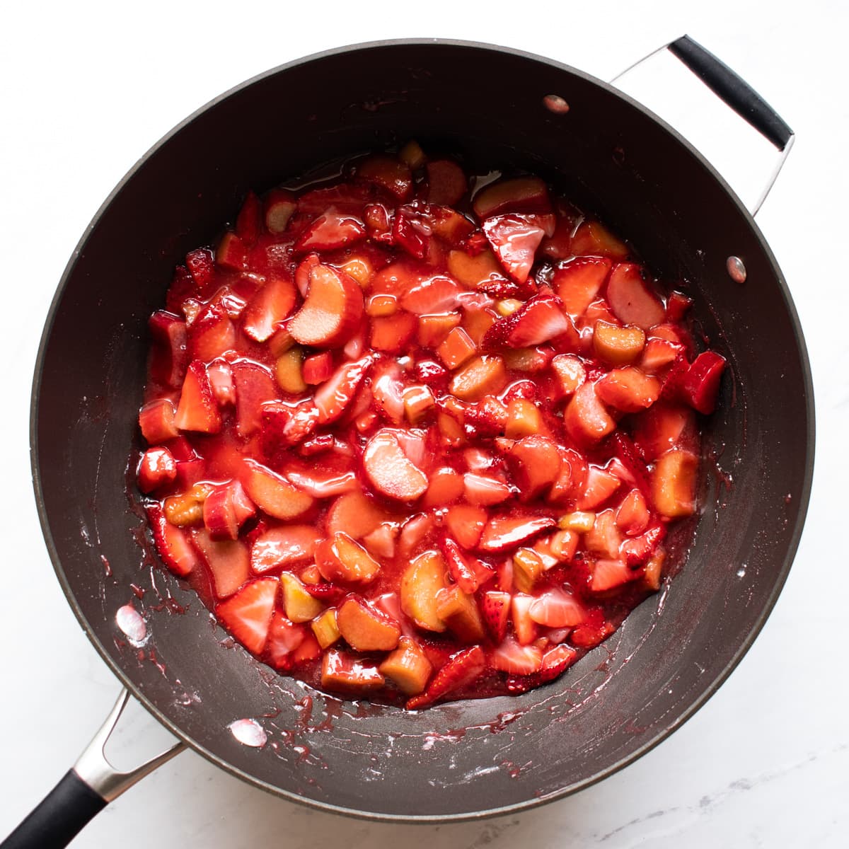 Strawberries, rhubarb, sugar, and cornstarch have been heated in a saucepan until syrupy. 