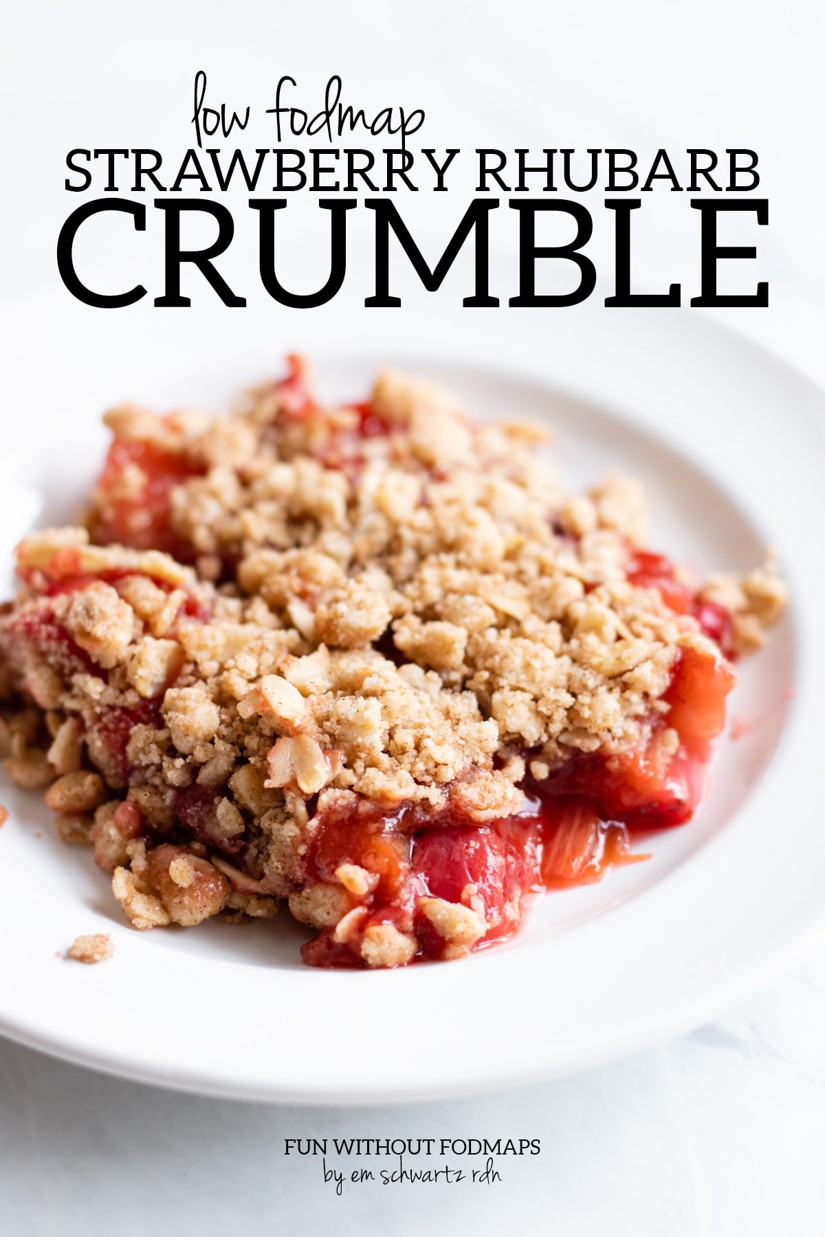 A close up of strawberry-rhubarb crumble on a white plate. Above the plate black text reads "Low FODMAP Strawberry Rhubarb Crumble" and below it "Fun Without FODMAPs by Em Schwartz RDN"