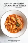 A white bowl filled creamy tomato-basil pasta. The bowl sits on a white marble countertop and above it a black text overlay reads Instant Pot Low FODMAP Tomato Basil Pasta with Chicken.