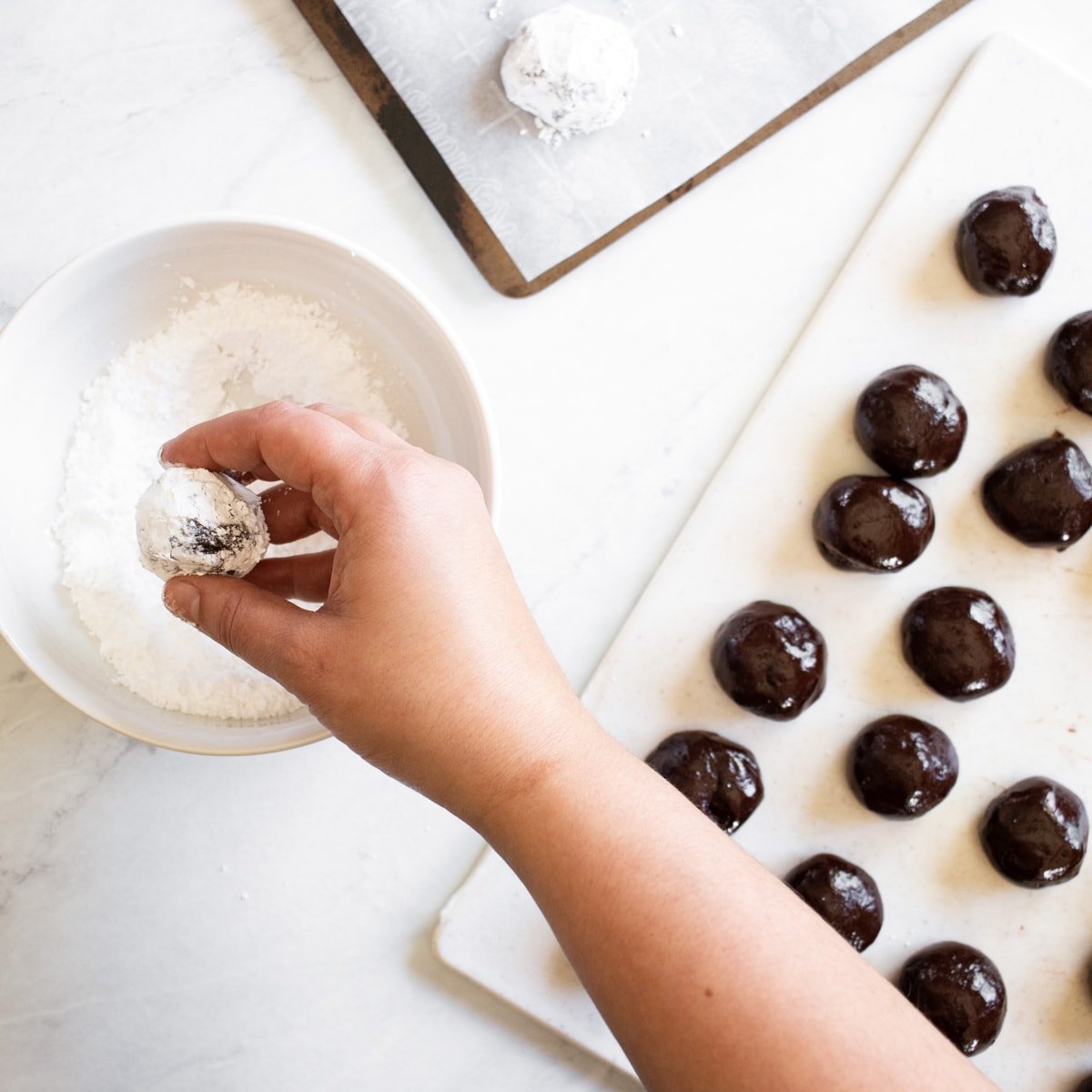 rolling cookie dough balls in powdered sugar