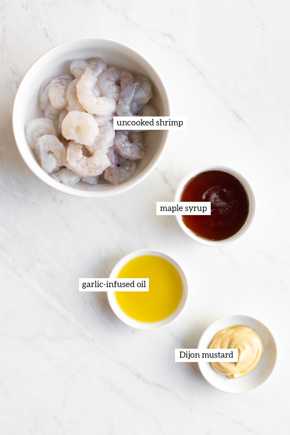 Ingredients needed for maple-dijon shrimp measured out into individual white bowls.
