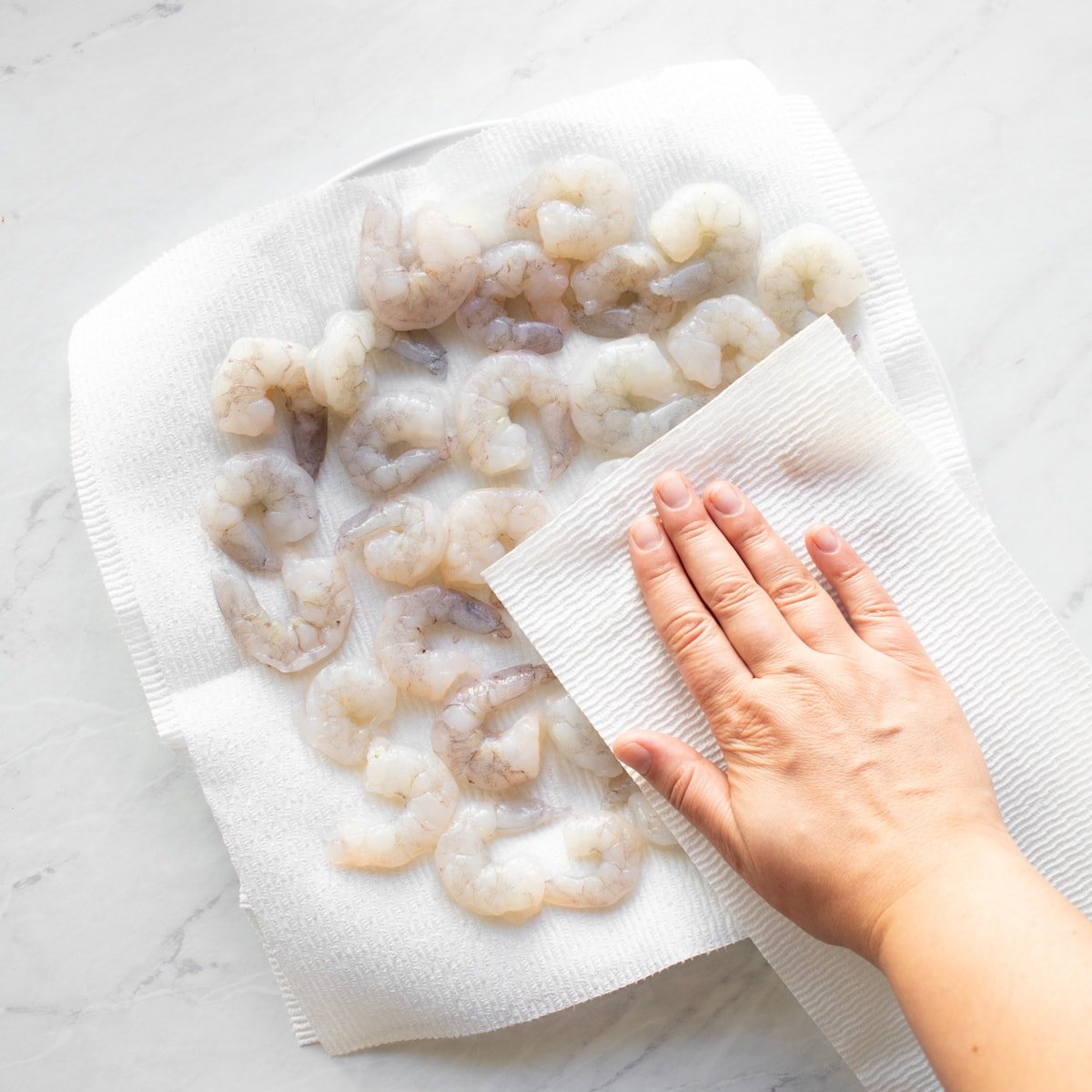 Patting shrimp dry with a paper towel.