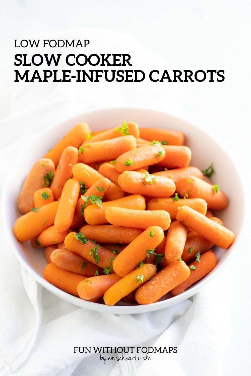 A bowl of cooked carrots topped with fresh parsley. In the white space above the bowl, black text reads "Low FODMAP Slow Cooker Maple-Infused Carrots."
