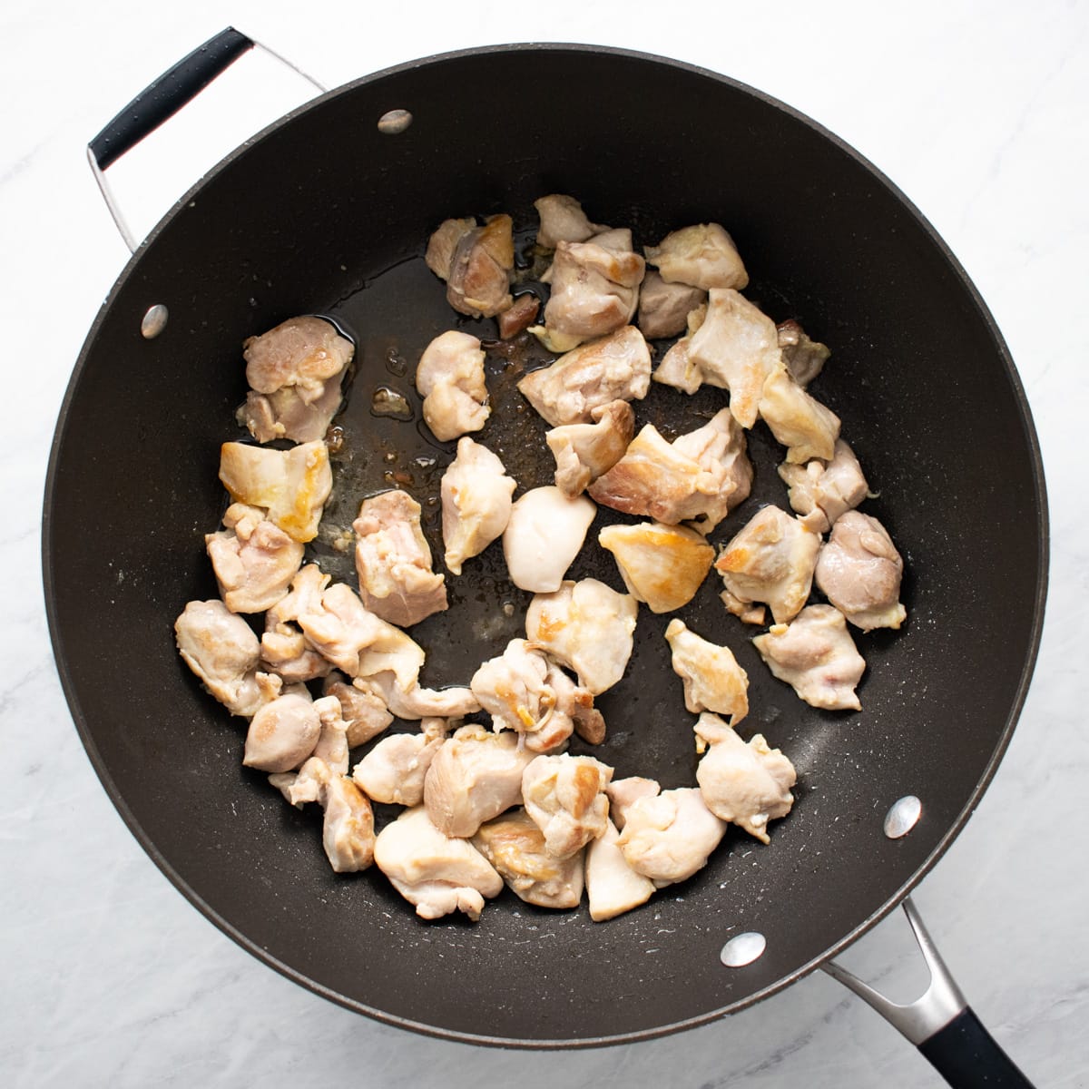 Browning chicken thigh pieces in a large skillet.
