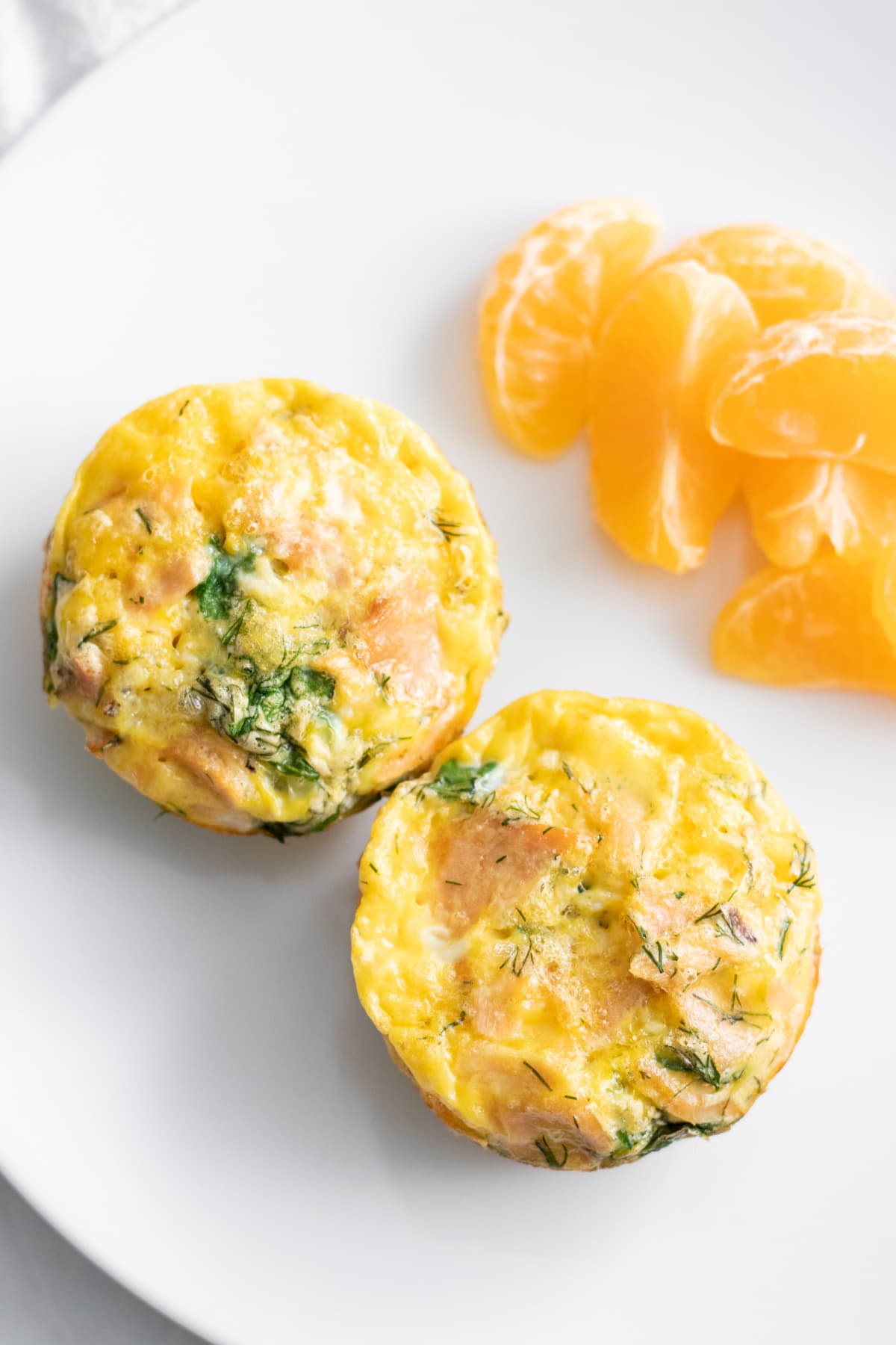 Two egg muffins on a plate with mandarin orange segments