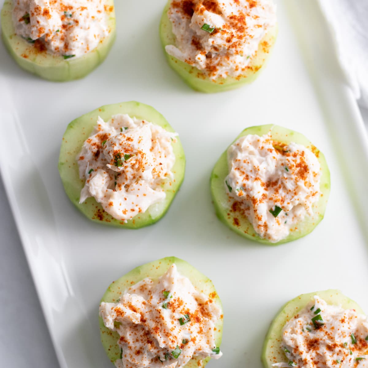 Cups made from cucumbers and stuffed with a crab mixture on a rectangular plate