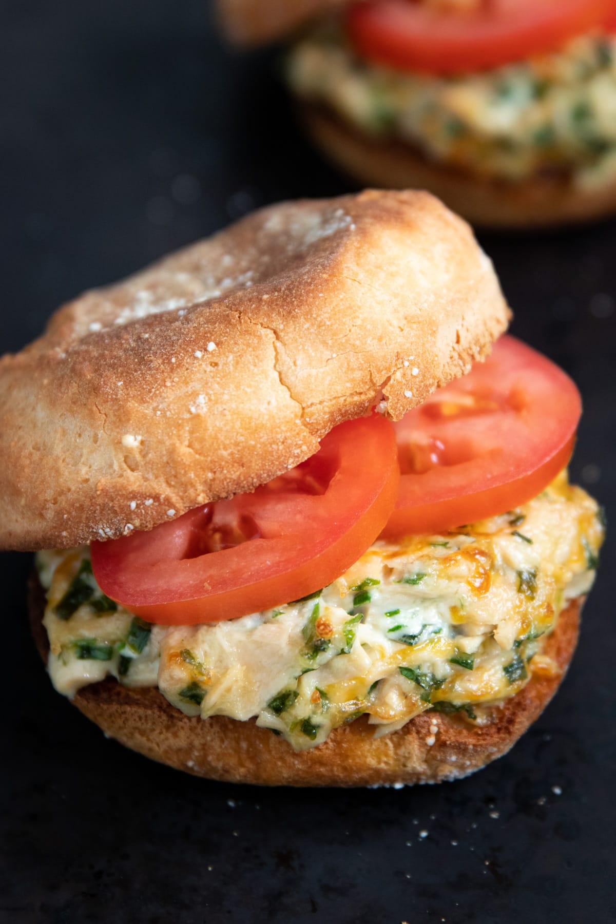 Canned tuna dotted with fresh herbs and melty cheese, topped with Roma tomato slices, and sandwiched in a toasted English muffin.
