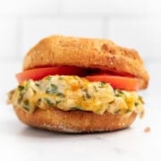 Close up of a tuna melt on an English muffin with tomato slices