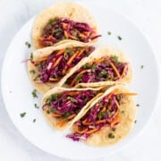 A plate of five tacos filled with Korean BBQ beef, pickled cabbage and carrots, and cilantro.