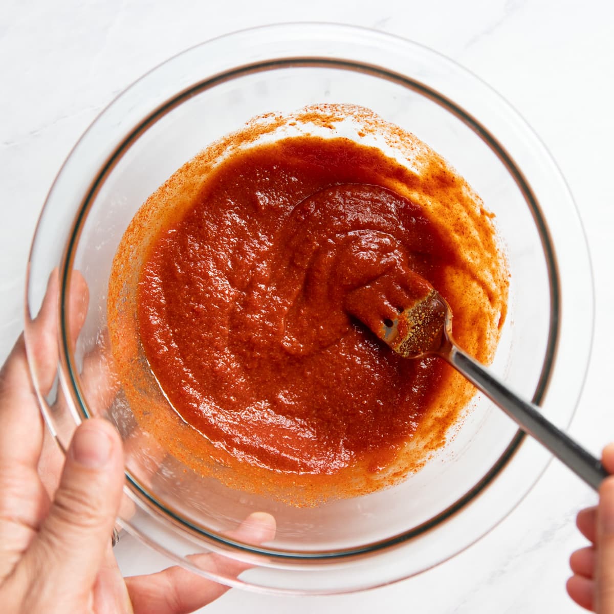 Stirring together a homemade low FODMAP taco sauce in a small glass bowl.