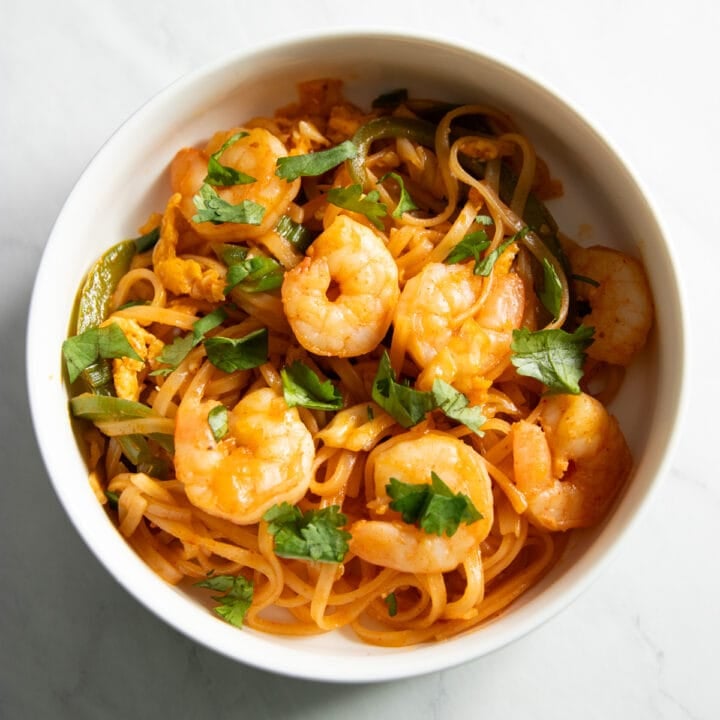 Looking down at a bowl of low FODMAP Pad Thai topped with cooked shrimp and fresh cilantro.