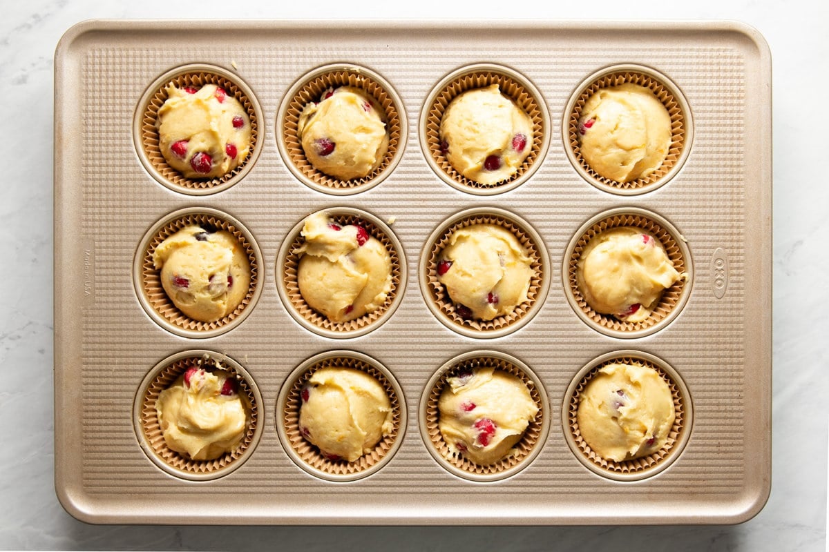 Muffin tin filled evenly with cranberry-orange muffin batter.