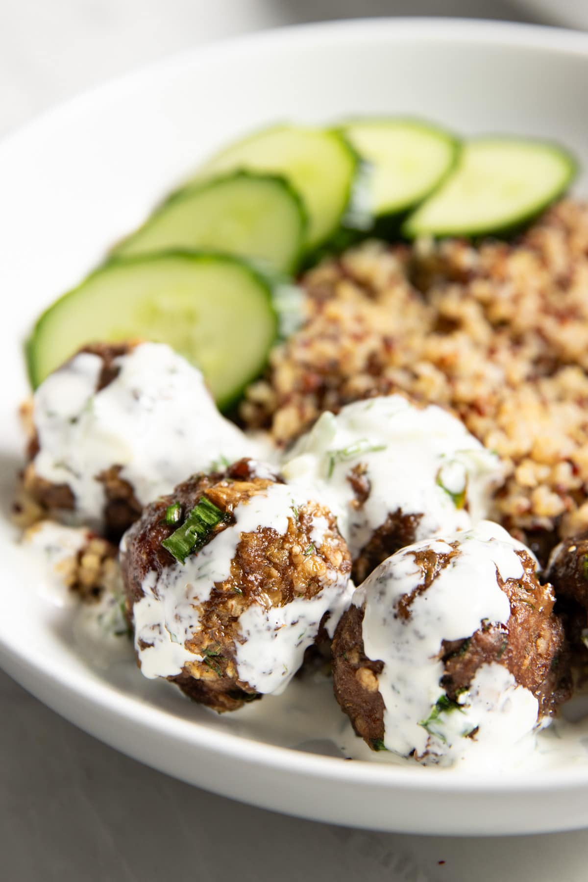 Close up of Low FODMAP Greek Meatballs drizzled with creamy cucumber-dill sauce.