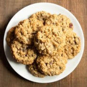 A white plate filled with low FODMAP trail mix cookies sitting a dark wood table.