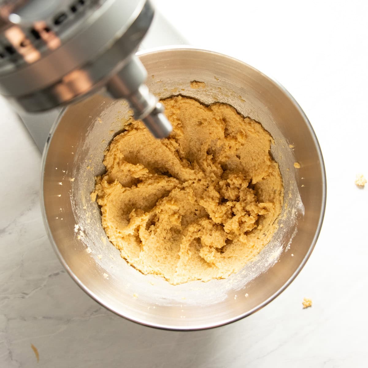 Stand mixer bowl filled with a mixture of butter, sugar, egg, vanilla, baking soda, and salt ready for the rest of the dry ingredients.