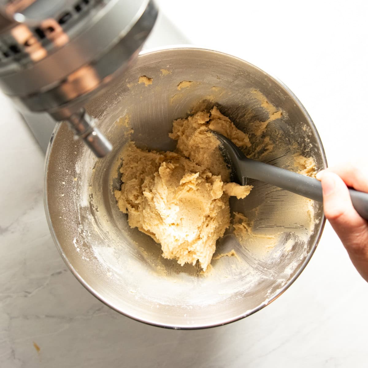 Stand mixer bowl containing butter-sugar mixture mixed with gluten-free flour needed to make cookies.