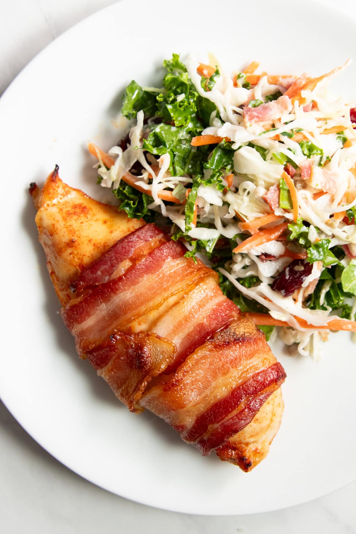 A plate with low FODMAP bacon wrapped chicken and sunflower crunch salad.