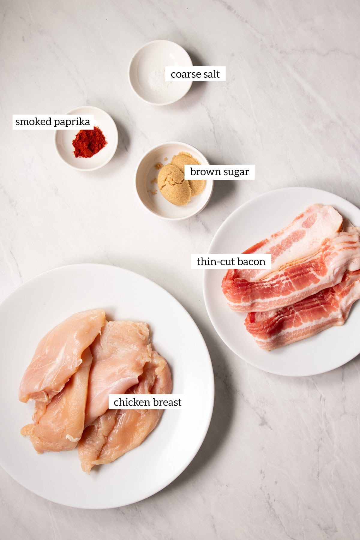 The ingredients needed for Low FODMAP Bacon Wrapped Chicken are prepared and measured out into individual white dishes.