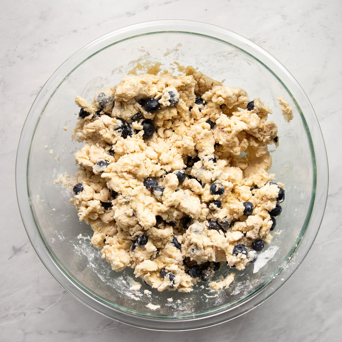 A large mixing bowl with fresh blueberries folded into scone dough.