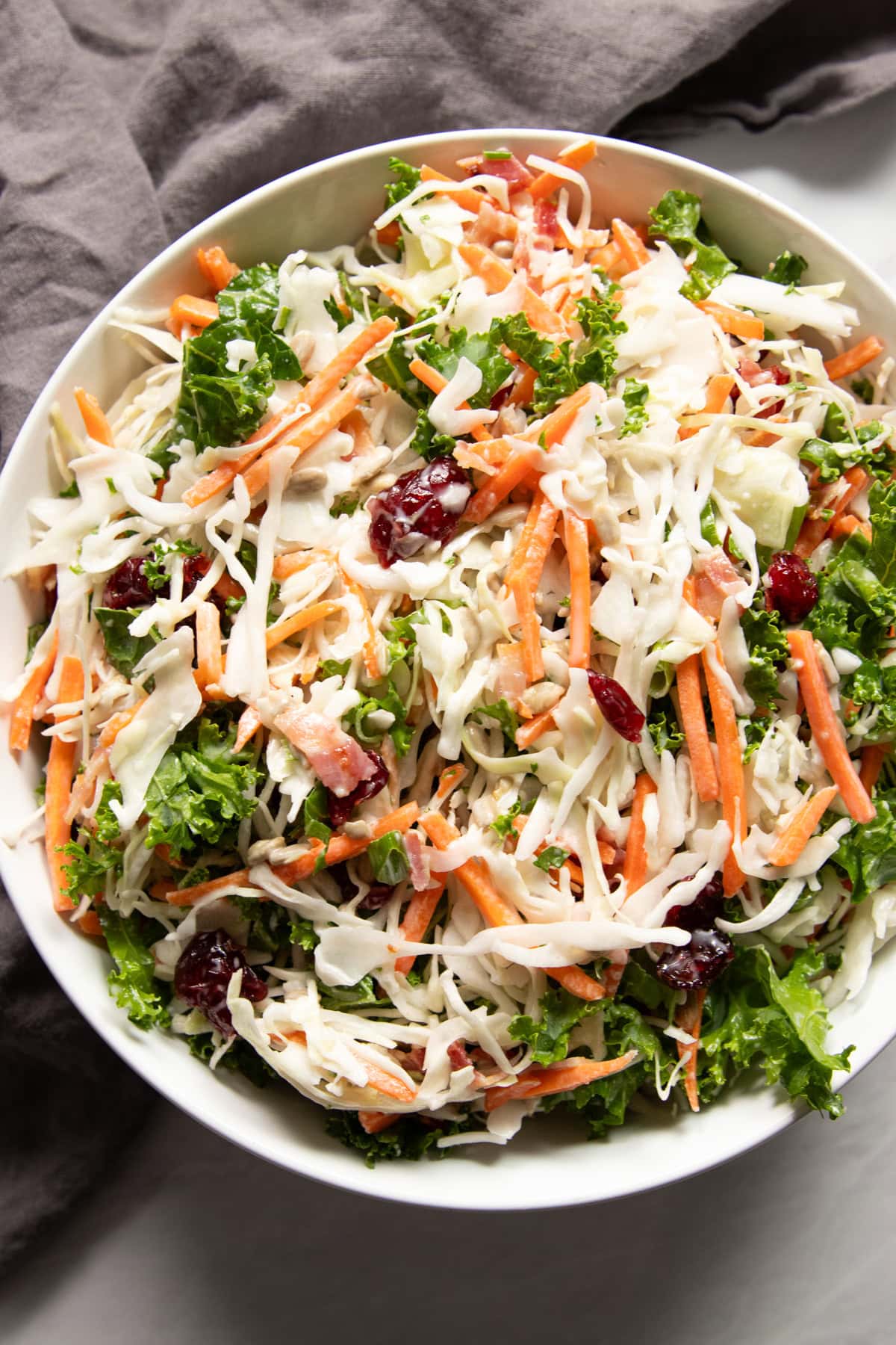 Looking into a bowl of low FODMAP sunflower crunch salad resting on a gray linen napkin.