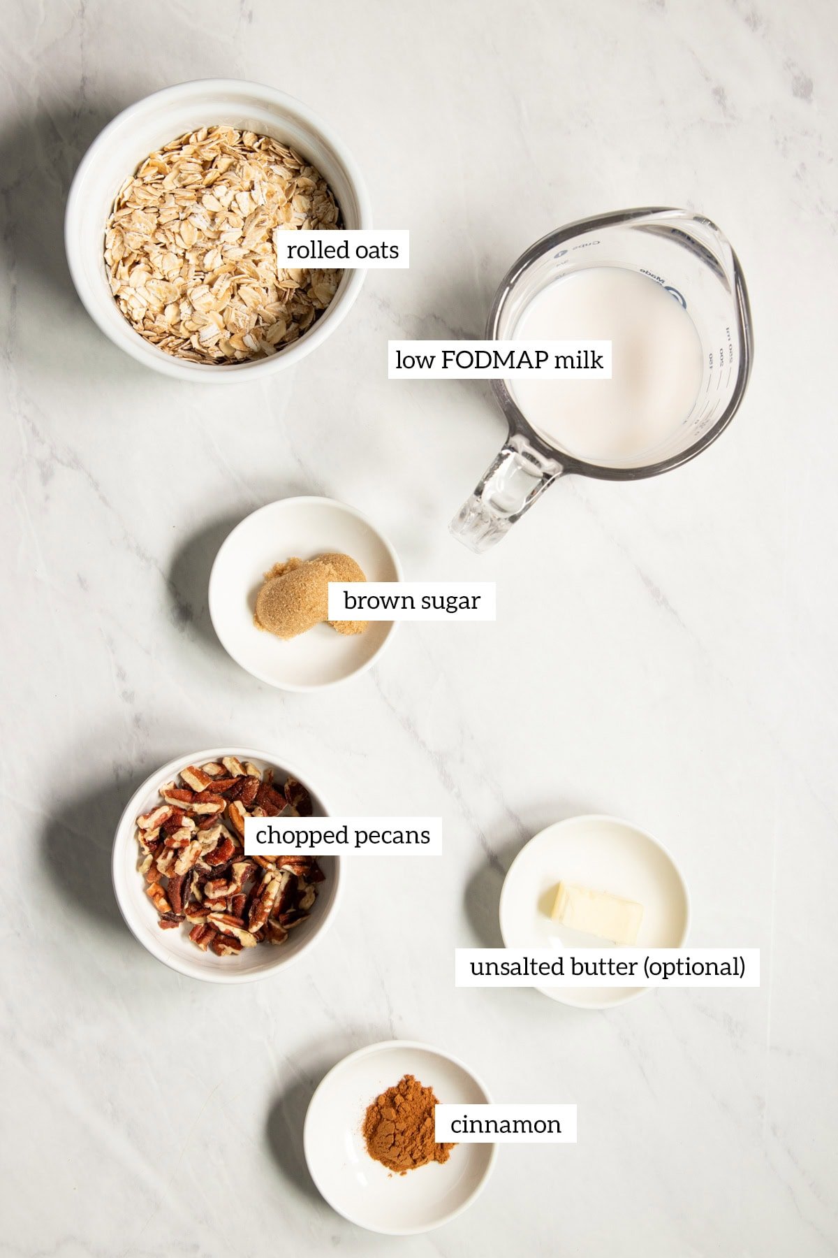 Ingredients needed for low FODMAP oatmeal with pecans and brown sugar and cinnamon are prepared and measured out into individual dishes. 