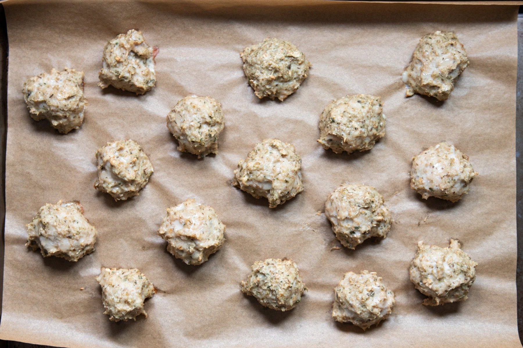 Baked chicken piccata meatballs on a baking sheet.