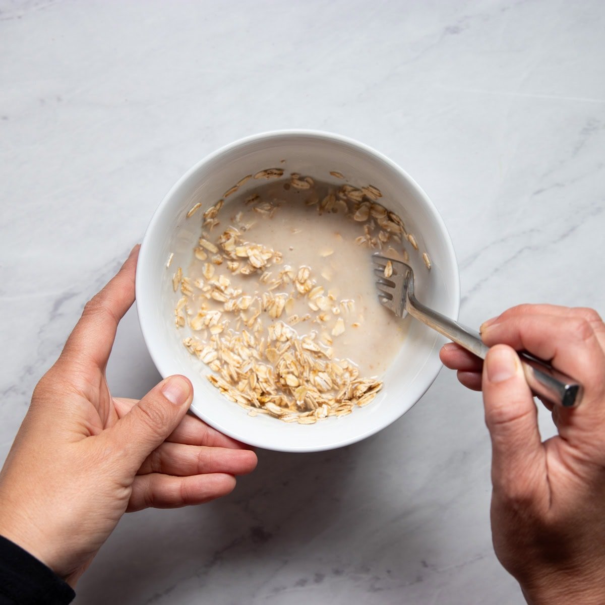 Stirring a bowl of oats and milk that has been microwaved for a minute.