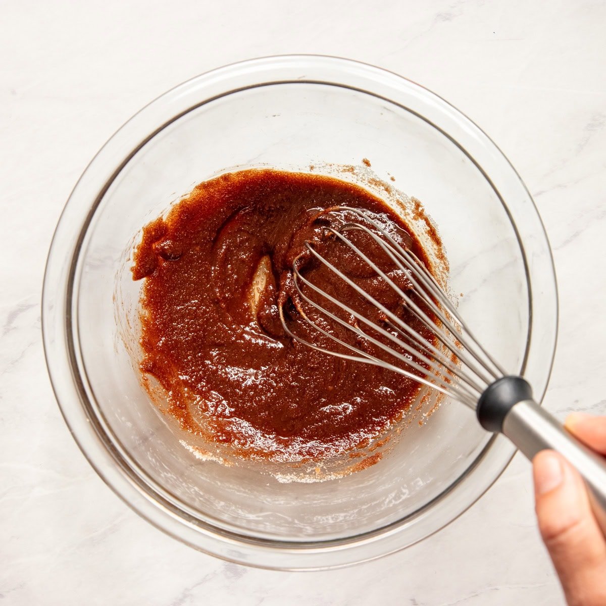 Whisking sugar into a melted chocolate and butter mixture.