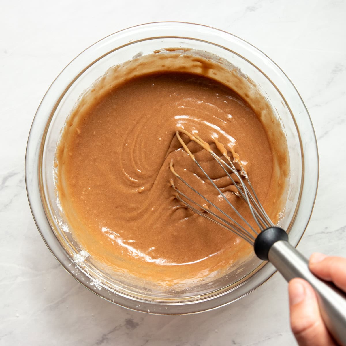Stirring low FODMAP flour, baking soda, baking powder, and salt into the wet ingredients for chocolate pecan waffles.