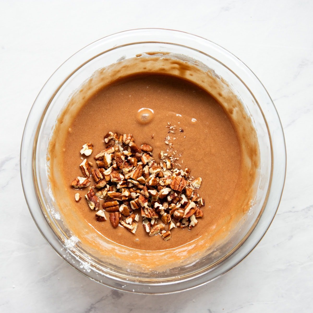 Folding finely chopped pecans into a low FODMAP chocolate waffle batter.