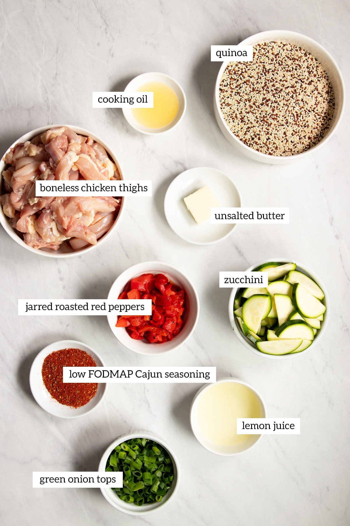 Ingredients needed for low FODMAP Cajun chicken skillet with quinoa and veggies are prepared and measured out into individual containers ready for cooking.