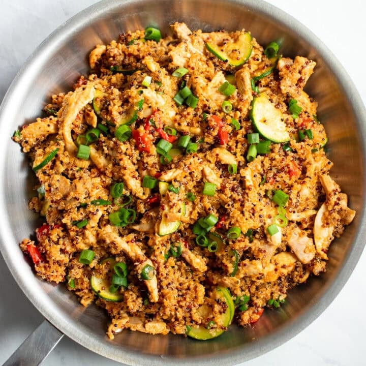 A skillet filled with Cajun season-flavored chicken, zucchini, and quinoa.