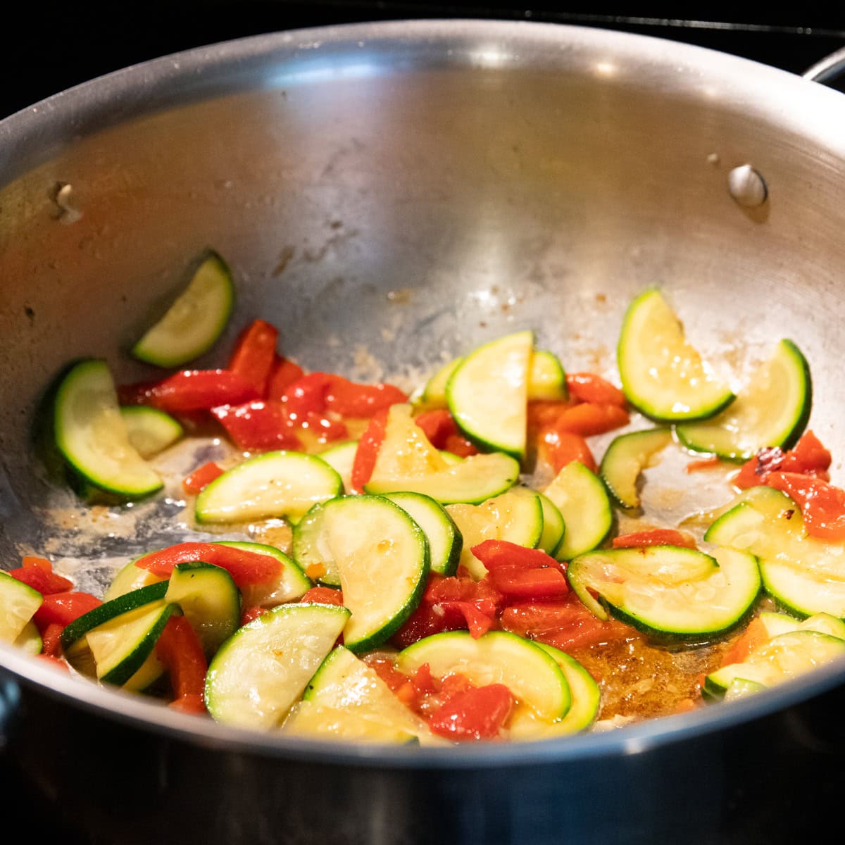 Sauteed zucchini and roasted red pepper warming in a skillet.