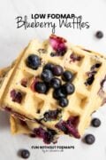 Looking down at a stack of blueberry waffles topped with fresh blueberries. In the white space, black text reads "Low FODMAP Blueberry Waffles."