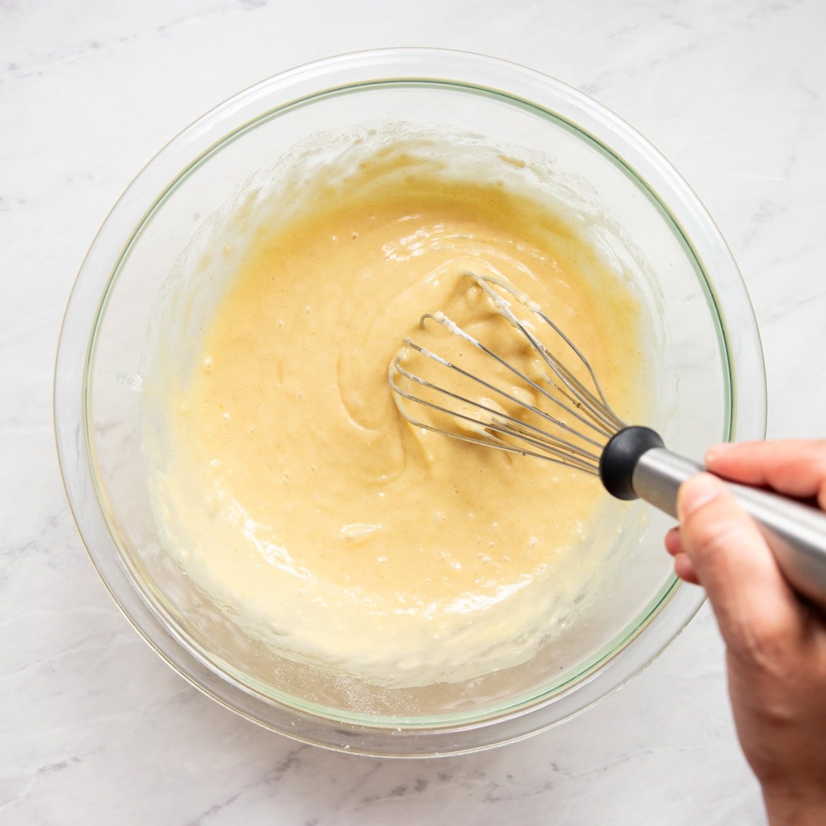 The dry ingredients and vanilla extract are being whisked in to make the base waffle batter.