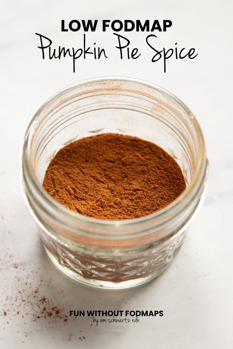 A small jar of a cinnamon brown spice blend on a white counter. In the white space above, black text reads "Low FODMAP Pumpkin Pie Spice."