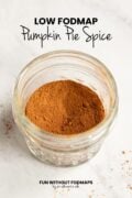 A small glass jar filled with a spice blend on a white counter. In the white space above, black text reads "Low FODMAP Pumpkin Pie Spice."