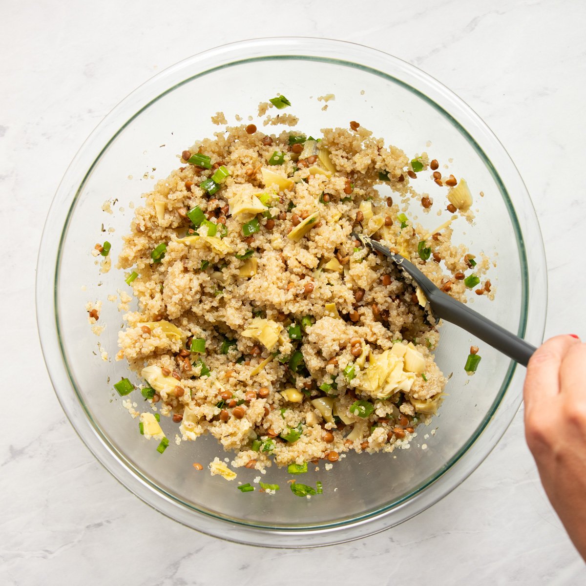 Mixing the low FODMAP lemon quinoa salad with a scoopula. 