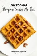 A waffle topped with chopped pecans and maple syrup on a plate. In the white space above, black text reads "Low FODMAP Pumpkin Spice Waffles."