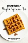 A waffle topped with chopped pecans and maple syrup on a plate. In the white space above, black text reads "Low FODMAP Pumpkin Spice Waffles."