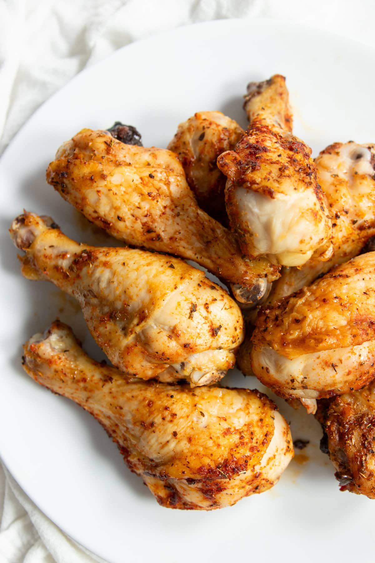 Looking onto a plate filled with baked chicken drumsticks. 
