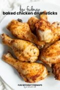 Looking onto a plate of roasted chicken. In the white space above, black text reads "Low FODMAP Baked Chicken Drumsticks."