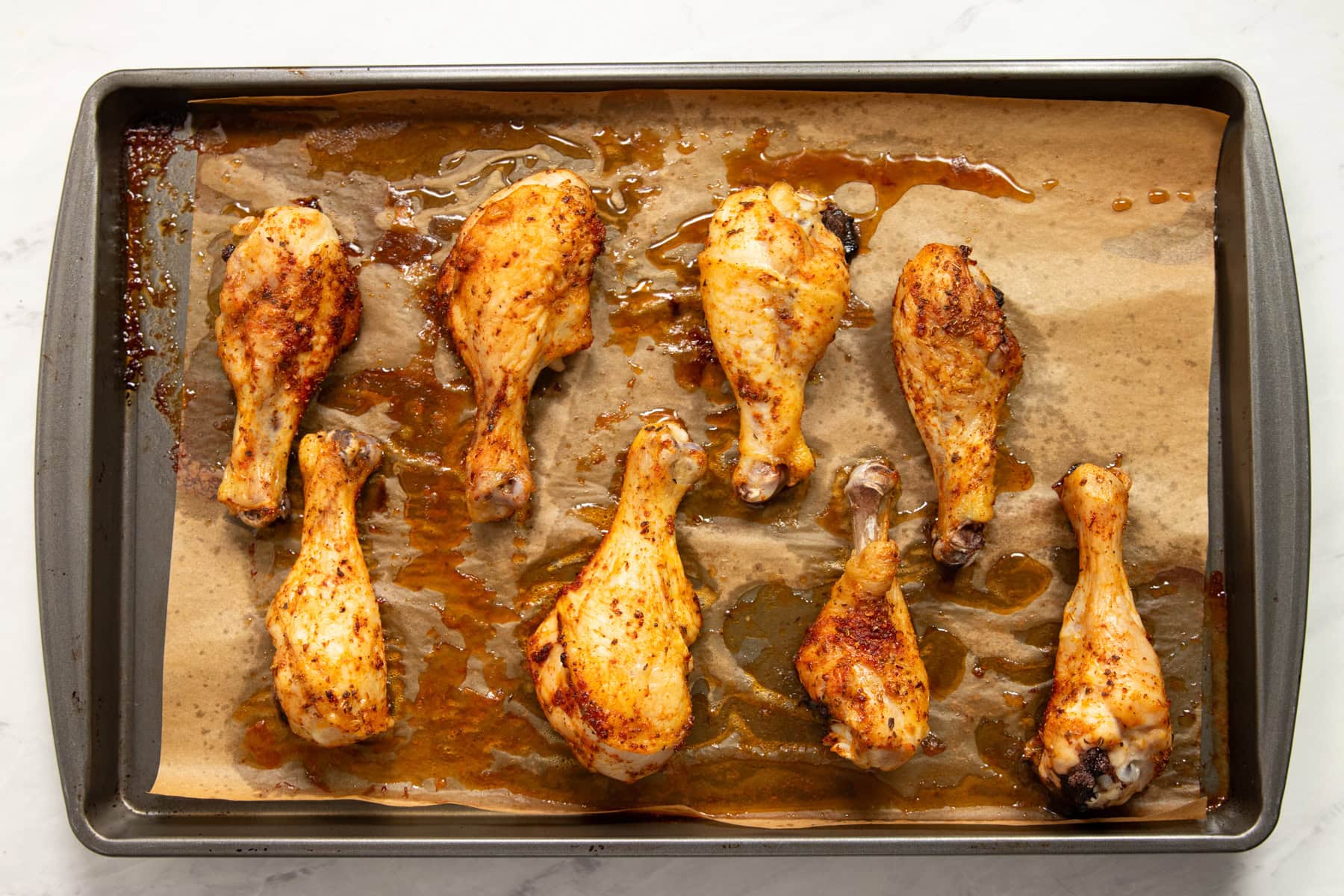 Golden brown Low FODMAP Baked Chicken Drumsticks are on a baking sheet lined with parchment paper and fresh out of the oven.