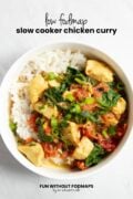 Looking into a bowl of curry with white rice topped with fresh cilantro and sliced green onion tops. In the white space above black text reads "Low FODMAP Slow Cooker Chicken Curry."