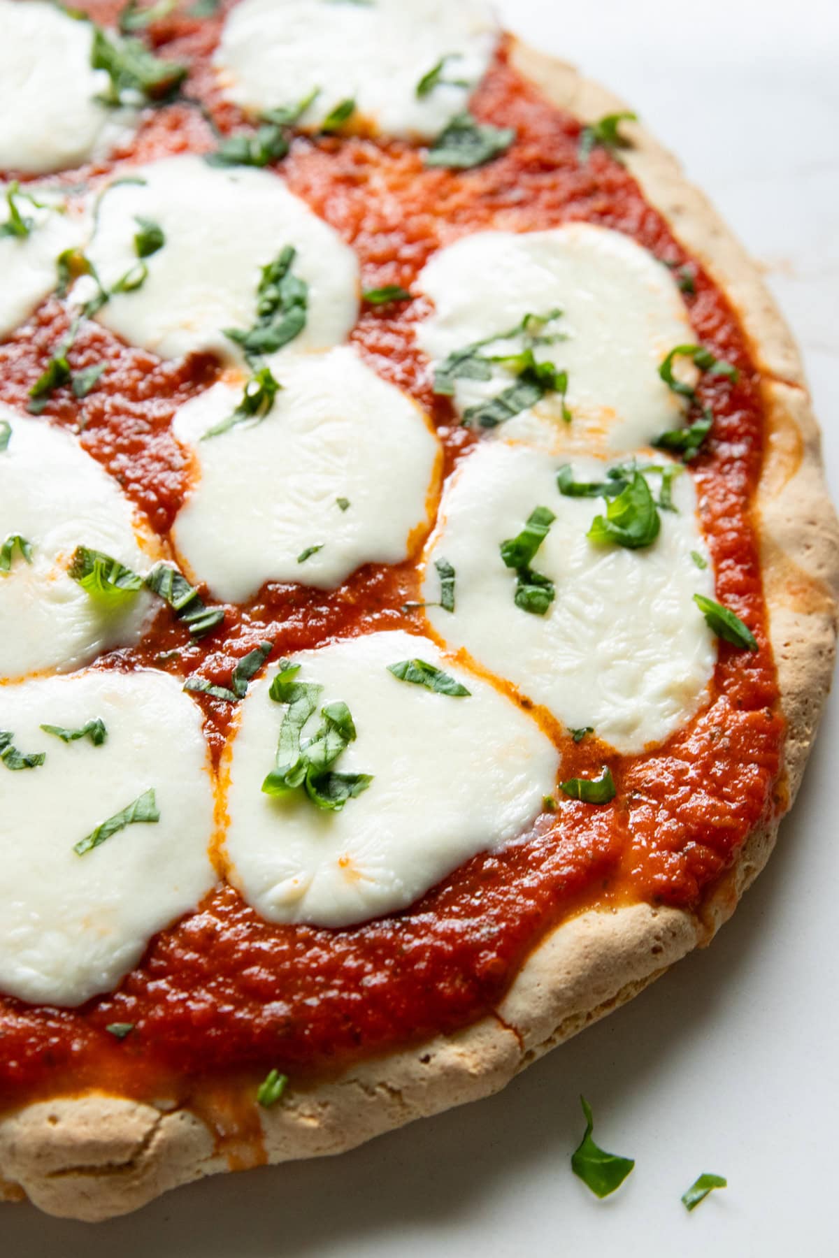 A low FODMAP cheese pizza made with a homemade gluten-free crust and pizza sauce and topped with melted mozzarella balls and fresh basil.