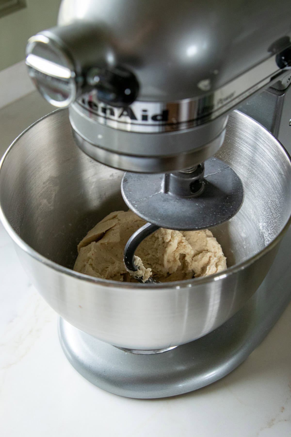 A gluten-free pizza dough ball forming in a stand mixer.